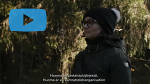 Ruutukaappaus videosta. Kuvassa nainen ulkoilemassa. Teksti: "Huoma on vertaistukijärjestö."